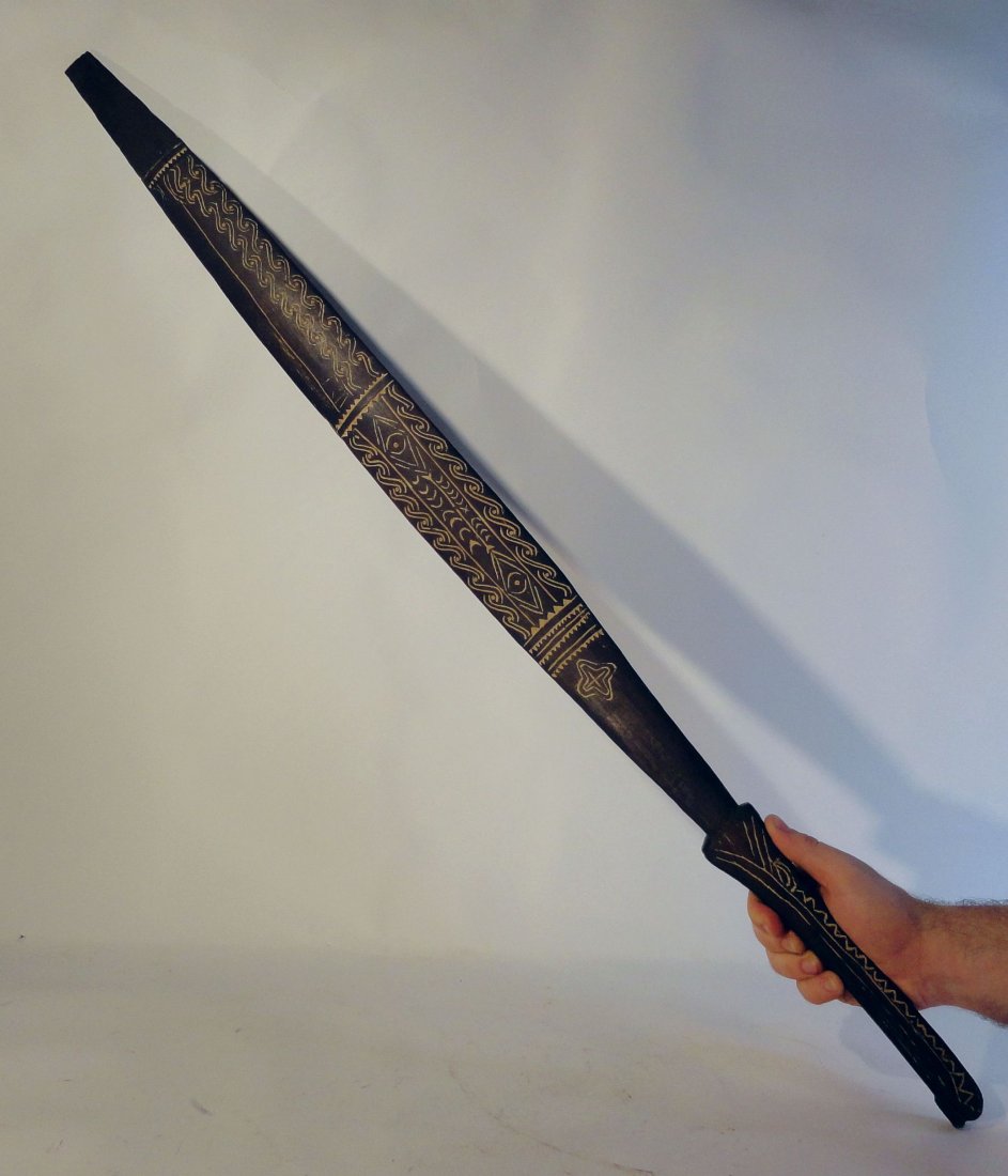 Solomon Island Sword Club Papua New Guinea Polynesian: Very rare Solomon Island sword club.This unusual club has an oblong shaped handle and a leaf shaped blade which is sharp on both edges and is incised with lime filled decorations. The wood is very den