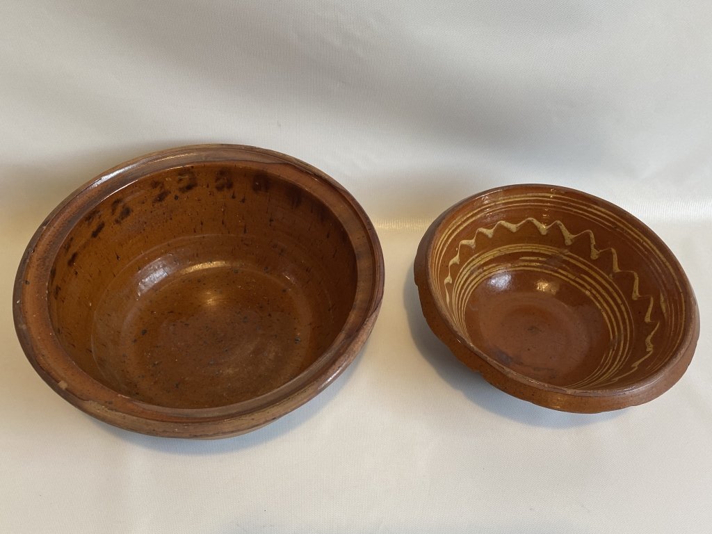 Pair of redware folk art pottery bowls.: Minor Chips on the rim of the large bowl. Chips on the rim and base-edge of the small bowl. Large bowl measures approximately 11” across x 4.5” high. Small bowl measures approximately 9.25” acro