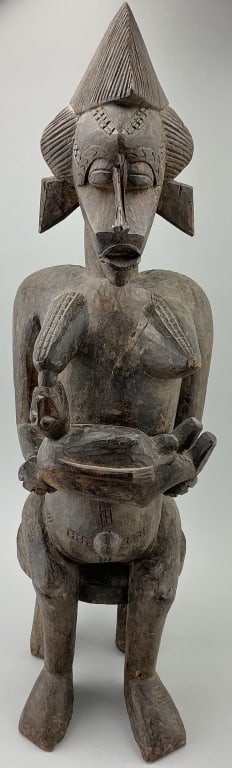 African Senufo Carved Iroko Maternity Sculpture.: 30.5"H. Carving depicts a seated woman nursing a child. Ivory coast, West Africa, Colonial period (1880-1914). Condition: Good with some minor loss and wear. **LOCAL PICKUP MUST BE BY APPT ONLY POSTAU