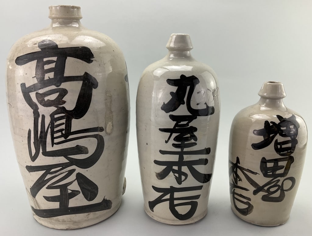 3 Japanese Glazed Stoneware Sake Bottles.: Measure approximately 10.5-15.5 inches high. Meiji period slightly tapered Kayoi Tokkuri which translates to "Commuter's Sake Bottle". The kanji calligraphy on the bottle denotes the name of the liquo