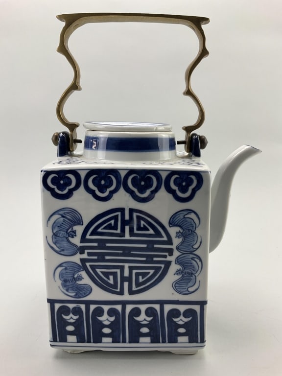 Reproduction Chinese Blue & White Porcelain Teapot: Measures 11 inches high, to the handle and 7.5 inches wide. Cobalt blue decorated rectangular body teapot with a brass handle. Decorated with Shou characters which symbolize longevity, also having sty