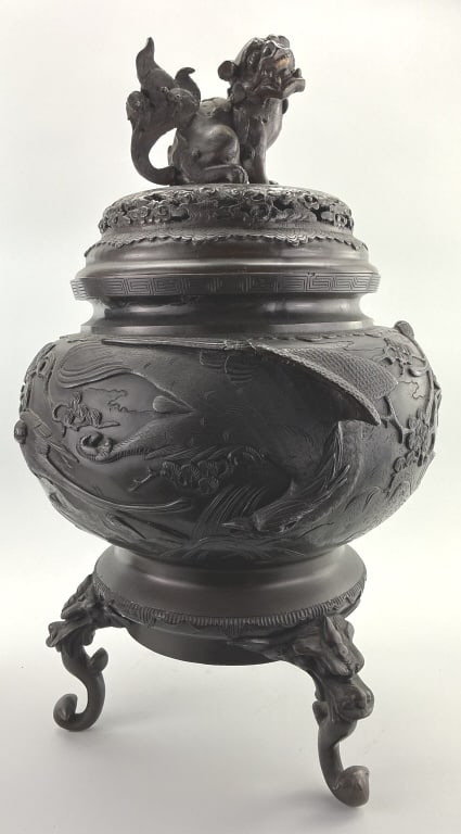Signed Japanese Meiji Period Footed Bronze Koro.: Measures 21 inches high by 12 inches. Signature translates "Made by Sekiguchi", Circa 1868-1912. Shishi finial on lid, globular body with high relief kacho-ga designs of birds and plants. Condition: V