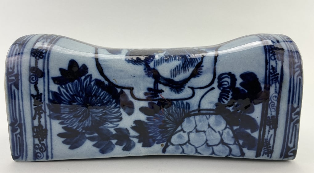 Reproduction Chinese Blue & White Porcelain Pillow: Measures 12.25 inches wide. Porcelain pillow headrest with under-glaze blue and white decoration featuring perched bird, chrysanthemum and foliate decoration. Painted Chinese character mark to each si