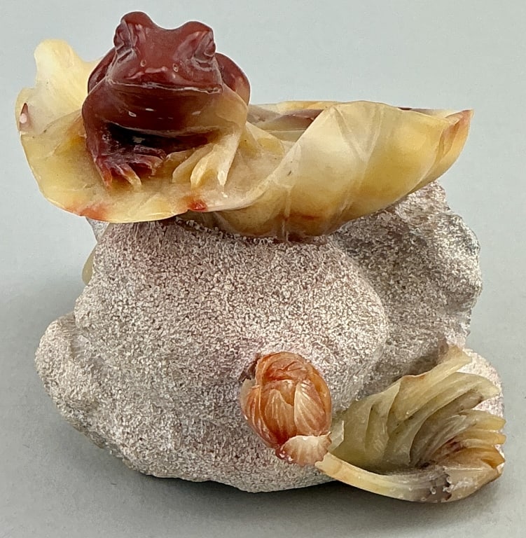 Chinese Carved Agate Frog Atop Lotus Leaf.: Measures 3 inches high. Hand carved sculpture featuring a frog atop a lotus leaf with surrounding stone elements that represent a lotus seed pod and flowers. Characteristic of Chinese art where the lo