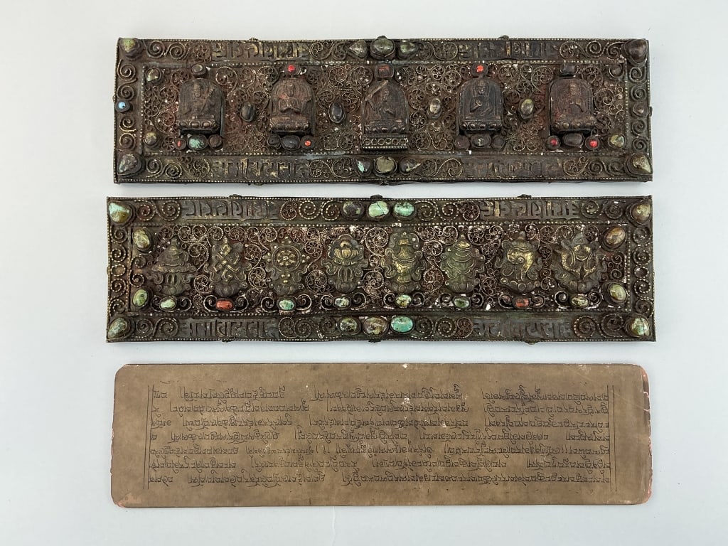 Antique Tibetan Buddhist Manuscripts with Covers.: Measure 14 inches wide. Qing Dynasty (1644-1911). Ink and watercolor on paper, covers are brass and silver wire filigree set with Buddhist figures and precious stones. Condition: Good with loss and we