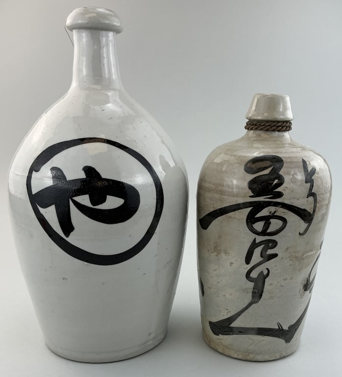Two Antique Japanese Glazed Ceramic Sake Bottles.: Measure 10.5 and 13.5 inches high. Meiji period (1868-1912), known as tokkuri, with hand-painted calligraphy indicating the sake brand and/or distillery. **LOCAL PICKUP MUST BE BY APPT ONLY POSTAUCTIO