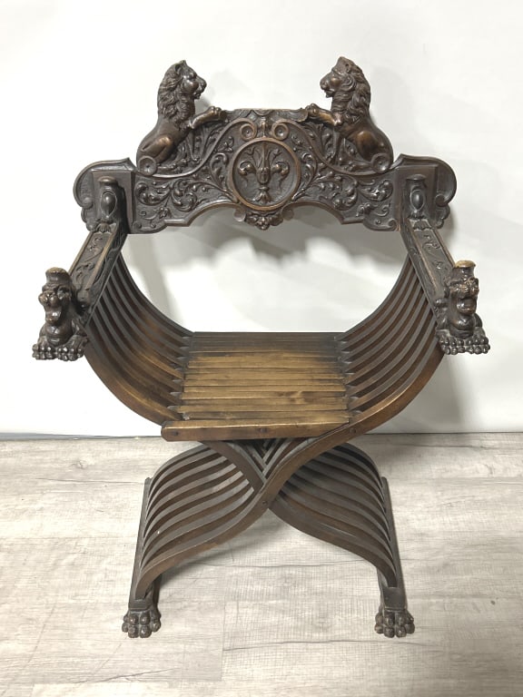 Italian Renaissance Carved Walnut Savonarola Chair: 38 inches tall x 26 inches arm to arm. Late 19th/early 20th century ornately carved X-frame armchair with rampant lion and foliate carve crest, lion carved arms scissors chair. The chair is named afte