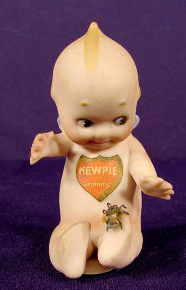 Shield Label Bisque Kewpie With Fly on Foot NR: Bisque Kewpie seated with a fly on its foot; good shield label on front, design patent label on back and bottom has the C in a circle mark. (No condition problems.) 3 1/4" T.