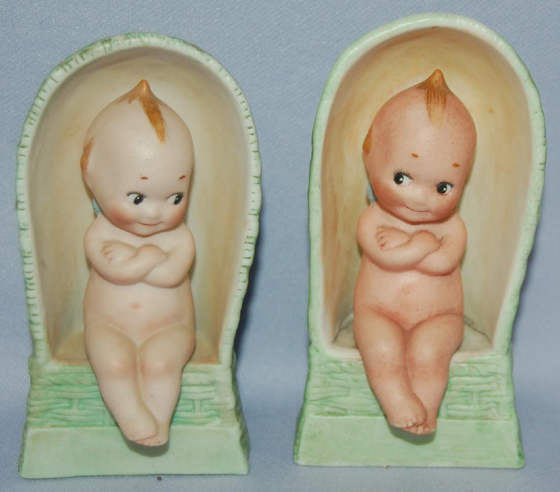 2 Antique German Bisque Kewpies: 2 Antique German Bisque Kewpies: They have painted features and are seated in green wicker hooded seats. They both are sitting with their arms crossed. The © mark is on them. Both sell as is, whe