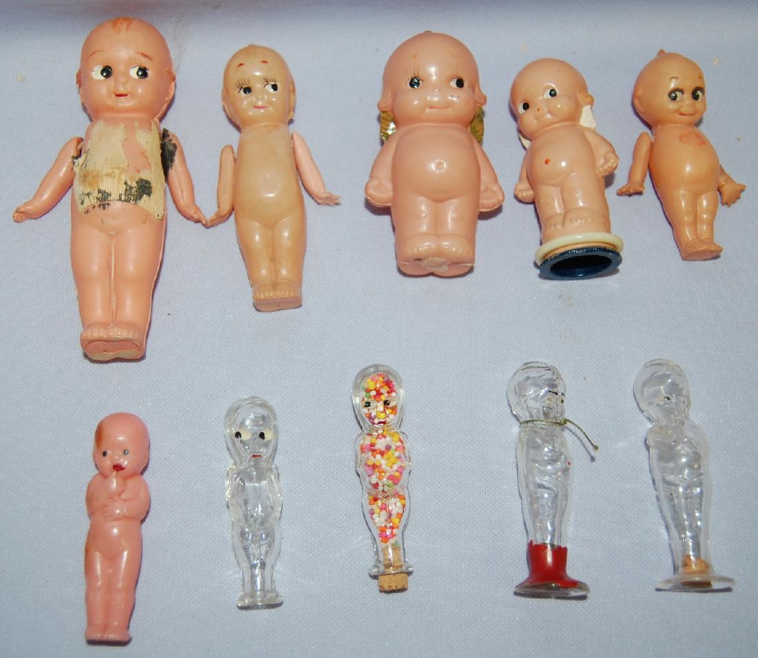 10 Antique Kewpie Dolls, Celluloid and Glass: 10 Antique Kewpie Dolls, Celluloid and Glass: 5 celluloid, Made in Japan, 3 with jointed arms, painted features, one pencil sharpener, 1 plastic. Tallest 5"; 4 glass Kewpie candy containers, 3 with co