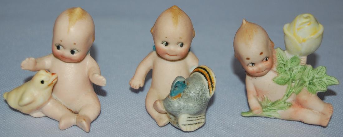 3 Antique German Bisque Kewpie Miniatures by Rose O'Nei: 3 Antique German Bisque Kewpie Miniatures by Rose O'Neill, painted features: 1.) Reclining with large yellow stemmed rose. 2" T; 2.) Seated, arms extended with yellow chick. (Broken and glued inside f