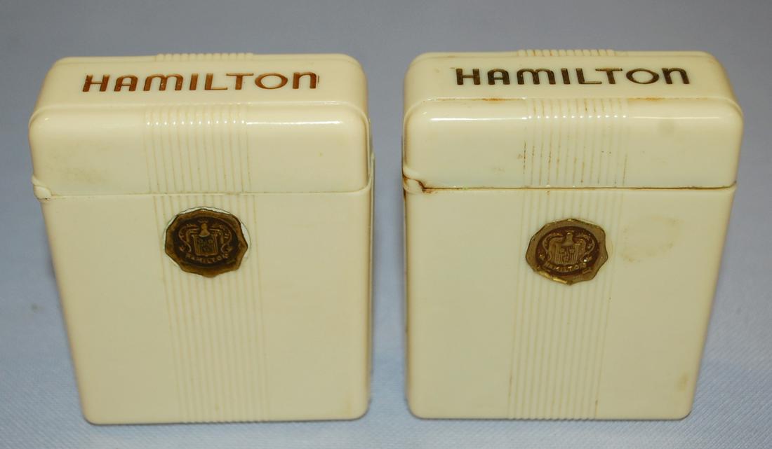 2 Hamilton Bakelite Watch Cases: 2 Hamilton Bakelite Watch Cases: both are in good condition, 1) darker color and has slight chip at hinge, Hamilton medallion in front has slightly curled edge, dark navy blue velvet. 2) lighter color