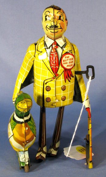 Marx "Butter and Egg Man" Tin Windup Toy: Tin Marx "Butter and Egg Man" Windup Toy: he holds a duck in one hand with "Eggs Laid to Order" on it. A satchel with "Fresh Country Butter" and form related items are in his other hand. (There is som