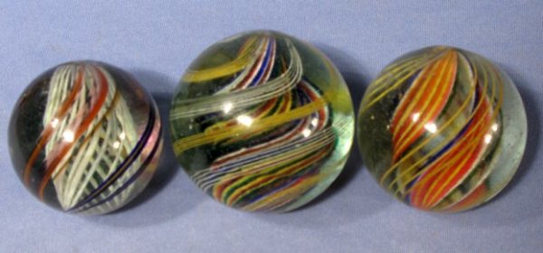 3 Marbles: Latticino & 2 Six Color Divided Core: 3 Marbles: Latticino & 2 Six Color Divided Core: 1.) 2 1/8" wide with 2 pontils. The twisted hollow core is red, white, blue, yellow and green. (Only minor surface problems.) 2.) 1 7/8" wide with 2 po