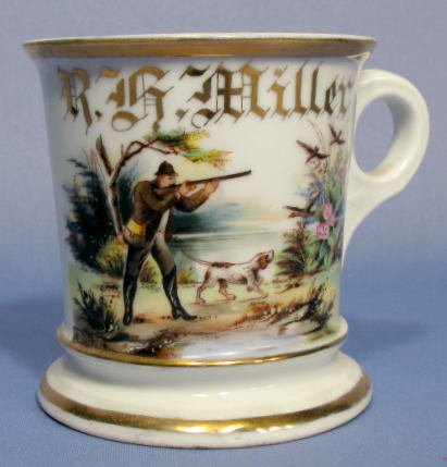 R.B. Miller Shaving Mug- Man Shooting Ducks: R.B. Miller Shaving Mug- Man Shooting Ducks: the scene includes a dog, flowering foliage, trees and the man aiming a shotgun. Unmarked. No condition problems. 4" tall All items sell As Is, Where Is, n