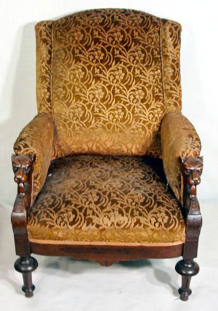 Upholstered Chair w/Dog Head Arms: Upholstered Chair w/Dog Head Arms: made of walnut and the dogs tongues are extended and resting on the front. The covering is brown and gold colored and shows lots of use. The chair looks to be from t