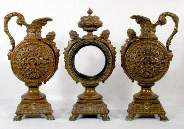 Ornate Iron 3 Piece Garniture Etruscan Clock Set: Ornate Iron 3 Piece Garniture Etruscan Clock Set: with winged angels. Nice set (No clock movement; wear, scuffs and scrapes to patina; needs clock set.) 14" T All items sell As Is, Where Is, no guaran