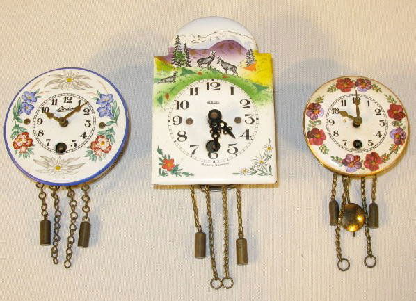 Group of 3 Miniature German Clocks: Group of 3 Miniature German Clocks w/Porcelain Faces: 1.) Linden with multi-floral décor, 2 3/4" wide (No pendulum) 2.) Heco with mountain sheep scene, 4" long (No pendulum) 3.) Round with red floral