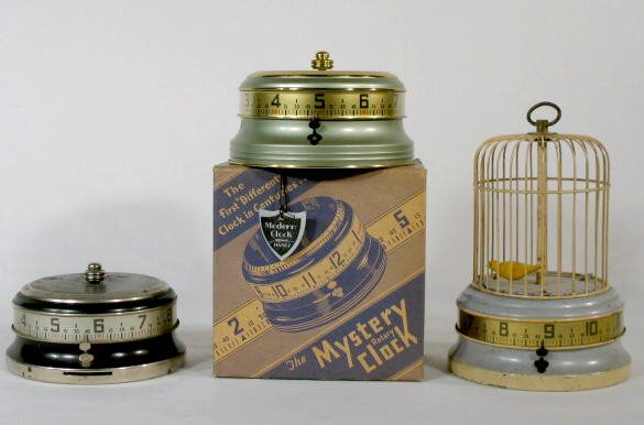 Group of 3 Mystery Rotary Clocks: Group of 3 Mystery Roatary Clocks 1. with coin bank base; black and nickel colored; working. (The surface is slightly worn.) 2 3/4" t x 5" w 2. 2.) Modern Clock Co. green & gold; new in box. Box is in
