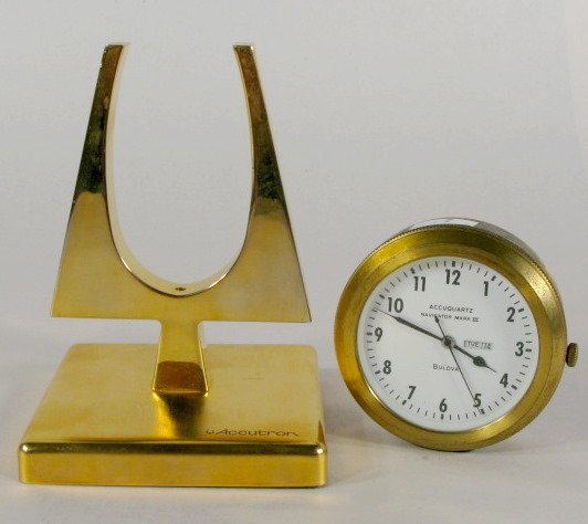 Accuquartz Desk Clock & Accutron Display Sign: Accuquartz Desk Clock & Accutron Display Sign: 1.) Accutron Emblem Brass Display Sign, 4 1/2" tall 2.) Accuquartz Navigator Mark III Desk Clock/Weight by Bulova with day and date. Brass case and 2" di