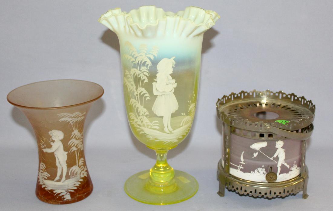 3 Mary Gregory Decorated Glassware Collectibles. 1.) A: 3 Mary Gregory Decorated Glassware Collectibles. 1.) A Warmer with boy and net, birds & trees metal frame and handle. 2.) Amber crackle glass vase with flared rim. 3.) Vaseline stemmed vase with girla