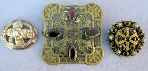 3 Brooches- 2 Sterling, 1 Art Nouveau: 3 Brooches: 1.) Scottish crown broach with garnets and blue glass beads. Marked 925. 1 1/2" wide 2.) George Jensen, Norway. Sterling with floral design. 1 9/16" wide 3.) Brass Art Nouveau, square with