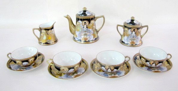 11 pc. Hand Painted Nippon Tea Set: 11 pc. Hand Painted Nippon Tea Set: decorated with clouds, lotus blossoms and immortals on a black and gold background. Consists of a teapot, creamer, covered sugar, 4 cups and 4 saucers. Marked in bl
