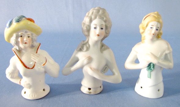 3 Pin Cushion Dolls, Minus Cushions: 3 Pin Cushion Dolls, Minus Cushions: 1.) Wearing a yellow feathered hat, marked Germany. 3 3/4" tall 2.) Gray hair with hands over breasts, unmarked. 4" tall 3.) Blond hair with green ribbon. Marked G
