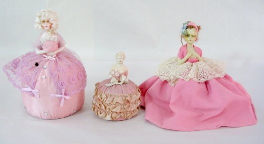 3 All Plaster Unmarked Pincushion Dolls: 3 All Plaster Unmarked Pincushion Dolls 1.) Largest with blonde hair and pink lace; 9 1/2" 2.) She has brown hair and bright pink gown; 8" 3.) This smaller one is all molded including her hair; 5 3/4"