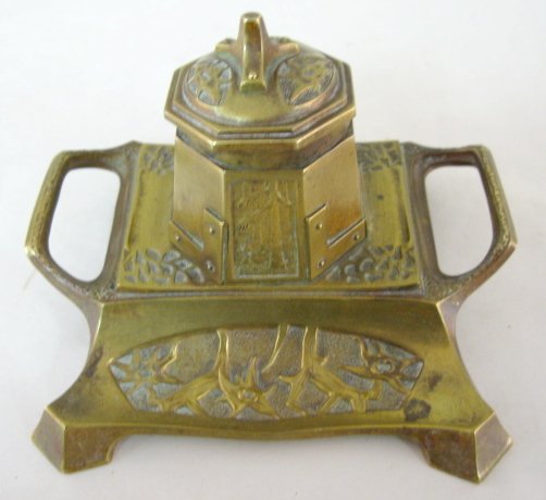 Brass Molded Relief Forest Inkwell Pen Holder : Brass Molded Relief Forest Inkwell Pen Holder: desk style with pen tray; two handles with octagan well; one panel hs a forest motif the rest are plain; lid has a 3 prong stump like appearance which tu
