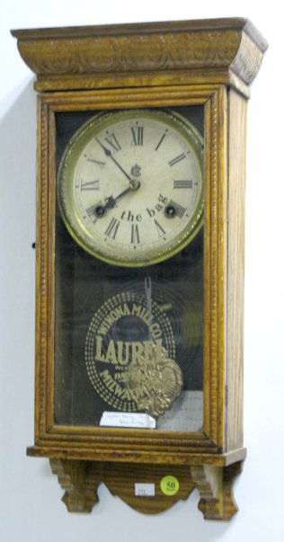 Waterbury Mini Hanging Regulator: Waterbury Mini Hanging Regulator: the dial and glass have advertising for Winona Mill Co. Flour. The company was from Milwaukee, Wis. The clock has an 8 day time with half hour gong striking movement.