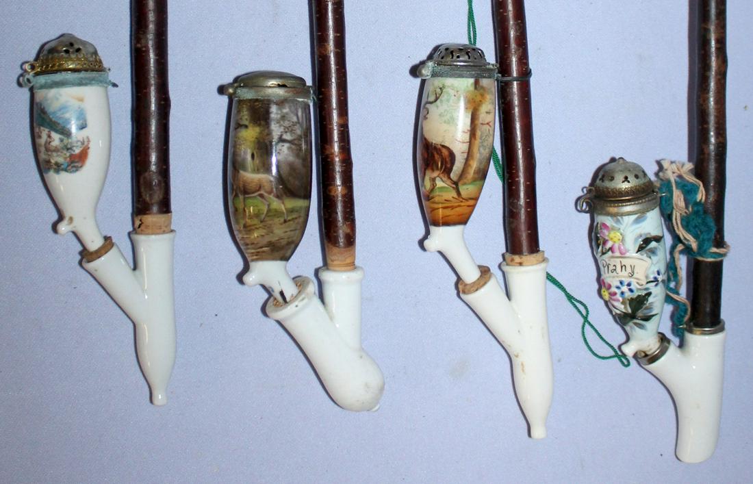 Four antique porcelain pipes w/m stems: Four antique porcelain pipes w/m stems. Elk standing over wounded dog, deer, mt. goats, flowers in relief. 17 1/2" L