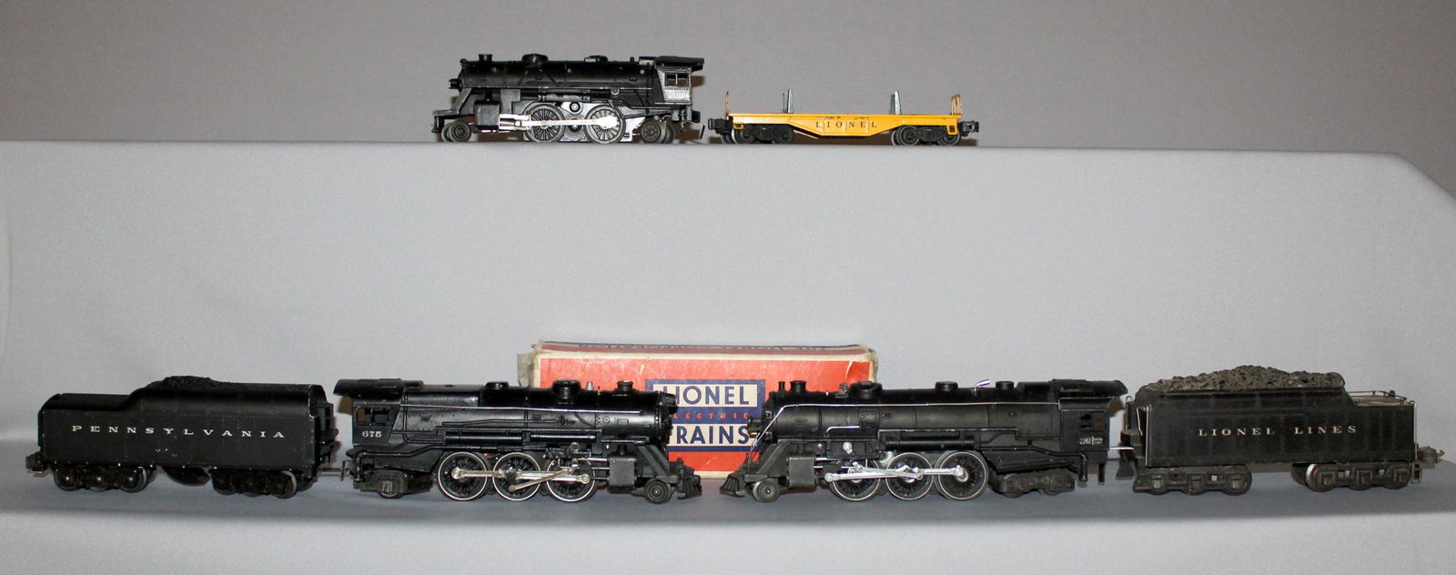 Lionel no. 675 engine, no. 2671W tender, no 2034: Lionel no. 675 engine, no. 2671W tender, no 2034 engine, no 226E engine and an unmarked tender, and an unmarked flat car. One tender has a box. The longest is 12" and all show use.