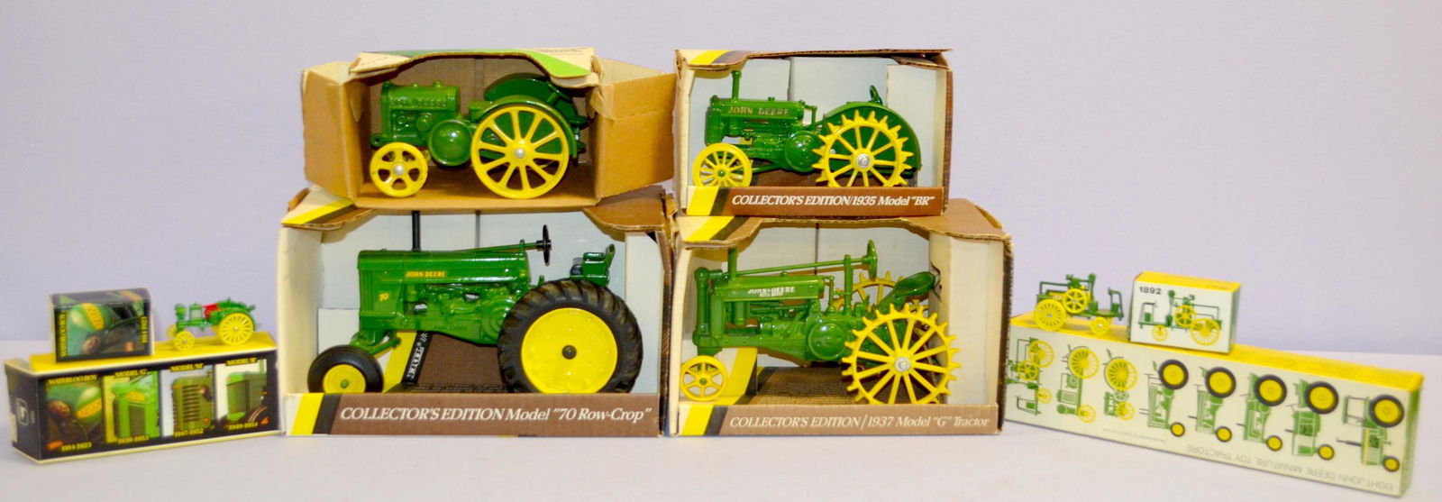 6 Ertl John Deere toy tractors in boxes: 6 Ertl John Deere toy tractors in boxes. 1- 4 pc set 1988. 2- set of 8 miniatures. 3- 1935 model 'BR'. 4- 1923 model D. 5- 1937 model G. 6- 1953 model "70 Row-Crop"