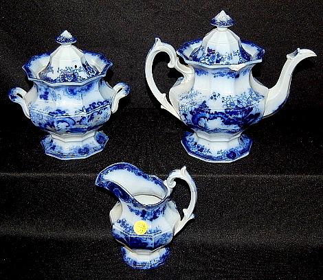 Flow Blue Coffee, Cream & Sugar: Flow Blue Coffee, Cream & Sugar: floral designs including a small sailing ship, not identified. 1.) Coffee pot, 9" (Has a large outer rim chip on one side and 2 smaller chips on the lids edge. The fin