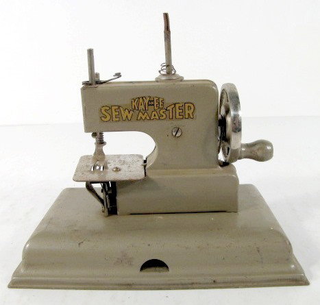German KAYanEE Sewmaster Toy Sewing Machine: German Berlin KAYanEE Sewmaster Toy Sewing Machine: marked Berlin on sewing plate; KAYanEE Sewmaster on sides. Works stiffly. (Corrosion to sewing plate.) All items sell As Is, Where Is, no guarantees