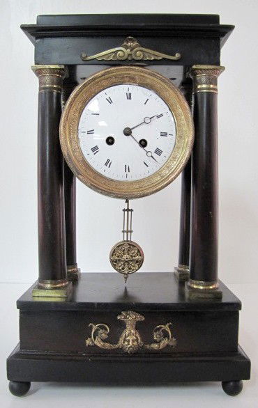 French Empire Column Clock: French Empire Column Clock: with metal mounts; lower one of a bearded man with fruit basket on his head; porcelain dial; has pendulum. (Does not wind or run; dial repaired; veneer missing off clock to