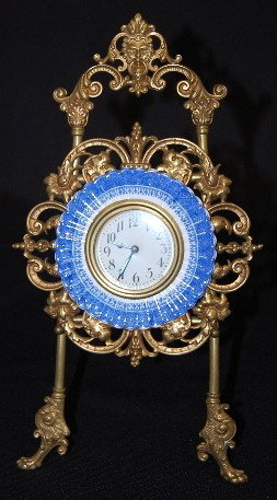 New Haven China & Metal Easel Clock: New Haven China & Metal Easel Clock: signed on dial; china plate frame on a metal griffin head, ornate cutout frame; metal easel has a man's head at the top and griffin feet on the front; plate is sig