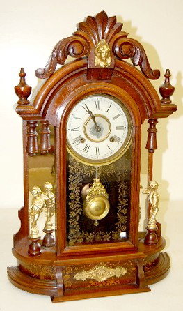 Walnut New Haven "Occidental" Parlor Clock: Walnut New Haven "Occidental" Parlor Clock: 8 day time and strike; 5 1/4" painted tin dial; has key and pendulum; gilt figures; gold floral decorated glass door. (Paint loss to dial; mirror shows plat