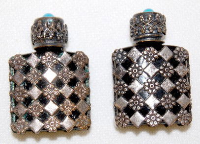 2 Miniature Ruby Glass Perfume Bottles: 2 Miniature Ruby Glass Perfume Bottles: both are encased in metal with floral and diamond designs. The lids have a small blue bead in them. Marked Made in France. 1 3/8" T."