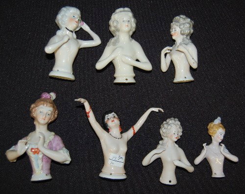 7 Porcelain 1/2 Dolls For Pincushions: 7 Porcelain 1/2 Dolls For Pincushions: none have cushions. Several have open or spread arms; some have gray hair. (One has damaged fingers.) Tallest 3 1/4"