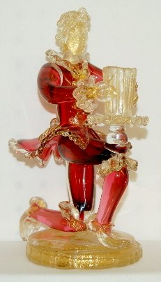 Murano Kneeling Male Cranberry Candlestick: Murano Kneeling Male Cranberry Candlestick: man has a tray and vase balanced on one knee; cranberry and clear with gold flecks throughout. (The vase is cracked.) 9 1/2" T