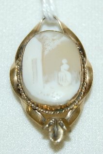 Carved Shell Cameo Pin/Pendant: Carved Shell Cameo Pin/Pendant: shown without much detail is a woman outside a building of some sort in an unmarked gold colored frame. 1 1/4" L