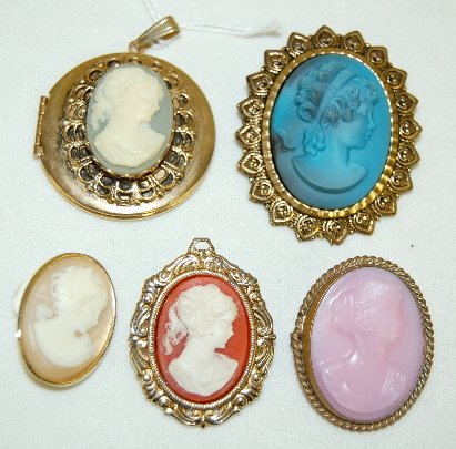 4 Cameo Brooches and a Locket: 4 Cameo Brooches and a Locket: 1.) Marked Western Germany; made of a molded blue porcelain like material; she is mounted on a fancy, pressed brass setting. 2" x 1 5/8" 2.) Molded pink glass on a 1 7/1