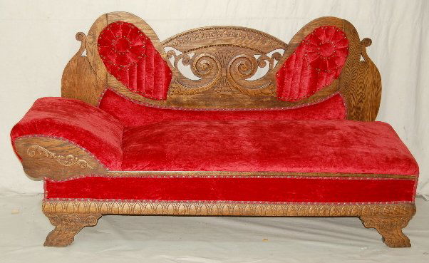Antique Carved Oak Fainting Couch/Bed: Antique Carved Oak Fainting Couch/Bed: w/ fancy frame; red velvet button tufted upholstery; folds out to become a bed; heavy construction. 42"T x 75"W closed; 42" x 75" x 46" when open. (Minor roughne