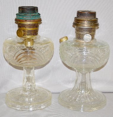 2 Aladdin Clear Washington Drape Lamps: 2 Aladdin Clear Washington Drape Lamps: round base, filigree stems; one nickel and one brass Model B burner; both have fill caps, they may not be original to the lamps.