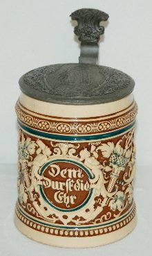 German Ornate Beer Stein, Lady: German Ornate Beer Stein: Merkelbach & Wick 1/2 liter; relief pottery with a stylized floral scrolling design with a motto in a medallion surrounded figures of a man and lady drinking; with an engrave