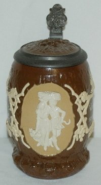 Mettlach V & B #1028 Beer Stein, Harvest Couple: Mettlach V & B #1028 Beer Stein: 1/2 liter; dark brown body with a tan relief design of a man carrying hay while walking with a woman; also has a verse on it; has an inset lid formed as a face; leaf a