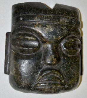 Native American Carved Stone Mask: Native American Carved Stone Mask: Made from a black stone with quartz bits; the notched head is wearing a head band; the eyes are thick grooves; the nose is flat and the mouth with the tongue tip is