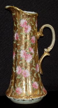 Antique Japanese Nippon Water Tankard: Antique Japanese Nippon Water Tankard: Has pink and white flowers and leaves in shades of green on a gold background; the gold has floral like designs on it; unmarked. (There is some worn gold on the 
